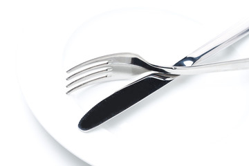 fork and knife on a white plate, close-up selective focus