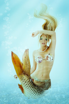 beautiful mermaid girl with fish tail and long blond hair swimmi