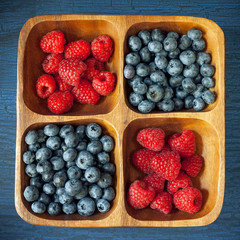 Raspberries and blueberries in a wooden bowl