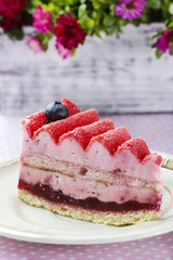 Pink layer cake decorated with fresh fruits on wooden table