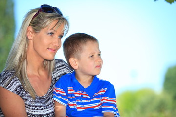 Happy family mother and son on bench in park