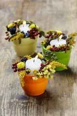 Candle holder decorated with autumn flowers and other plants
