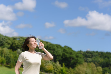 ペットボトルで顔を冷やす女性