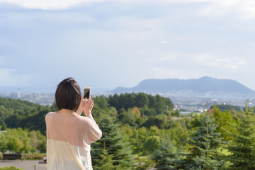 Obraz premium スマートフォンで写真を撮る女性
