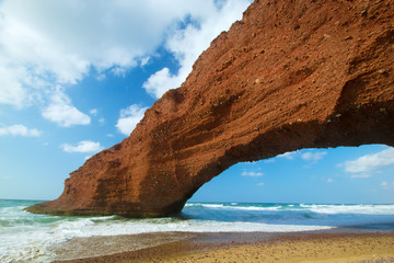 Huge red cliffs with arch on the beach Legzira