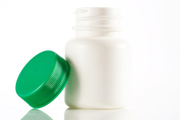 White empty medicine bottle standing with the cap at side