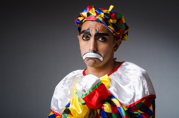 Sad clown against dark background