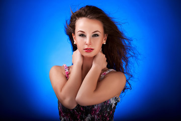 Naklejka premium Beautiful girl with hair in wind on blue background