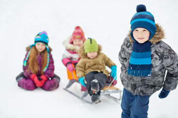 Boy pulls sledges with two younger children, focus on boy