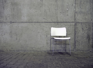 weißer stuhl vor betonwand