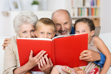 großeltern und enkel schauen hinter einem buch hervor