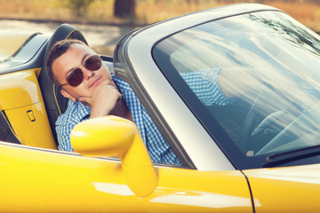 Male trendy model posing in yellow convertible car.