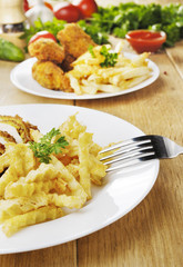 French fries and chicken on the plate on the wooden table