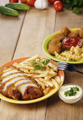 French fries and chicken on the plate on the wooden table