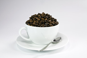 White ceramic cup with roasted coffee seeds.