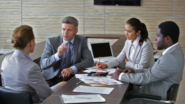 Group of multi-ethnic business people engaged in discussion during meeting in boardroom. Perfect for business strategy, teamwork and professional negotiations visuals