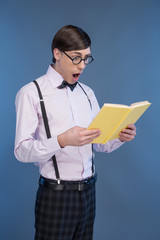 Nerd with book. Young nerd man reading book while standing isola