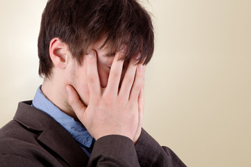 Young man holding his hands over his face