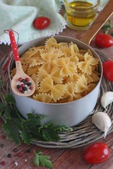 Pasta ( farfalle ) with ingredients on wooden background