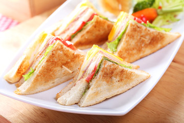 Sandwich with bacon and vegetables on white dish