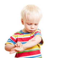 Kind schaut sich Verletzung am Arm an