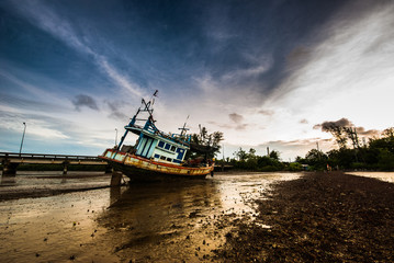 Fishing boat ran aground on the mud beach with the morning ligth