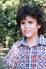 Outdoor portrait of a handsome boy with long curly hair