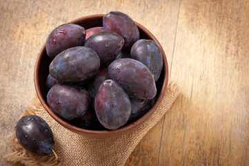 Plums in bowl on wooden table