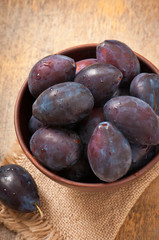 Plums in bowl on wooden table