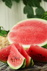 Ripe watermelons on wicker tray  on table on wooden background