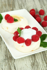 Tasty meringue cakes with berries on wooden table