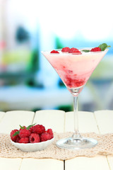 Raspberry milk dessert in cocktail glass, on bright background
