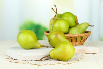 Pears on wooden cutting board, on light background