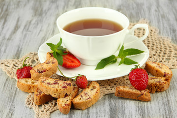 Cup of tea with cookies and strawberries on table close-up