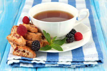 Cup of tea with cookies and berries on table close-up