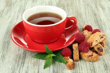 Cup of tea with cookies and raspberries on table close-up