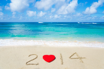 Number 2014 with heart shape on the sandy beach