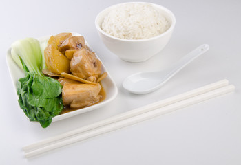 Chicken with rice and vegetables in background