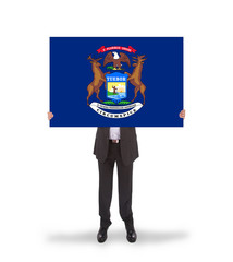 Smiling businessman holding a big card, flag of Michigan