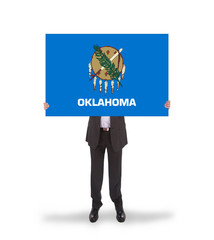 Smiling businessman holding a big card, flag of Oklahoma