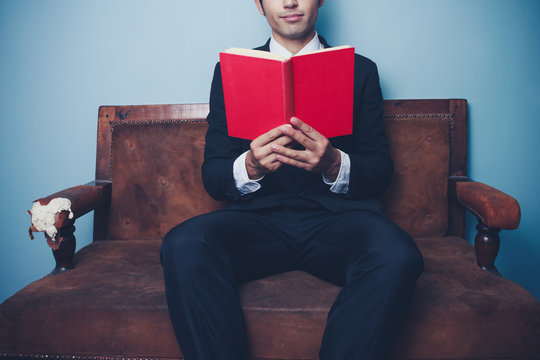 Businessman on sofa is reading