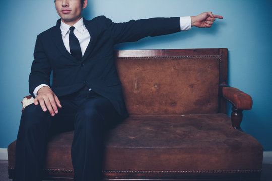 Businessman on sofa pointing right