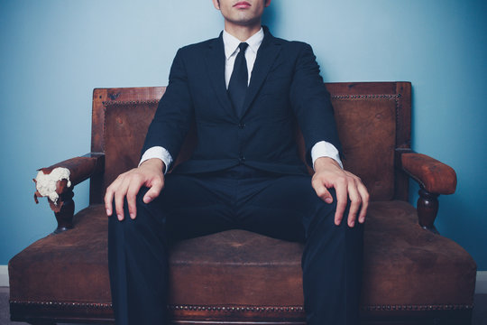 Young businessman on sofa in powerful pose