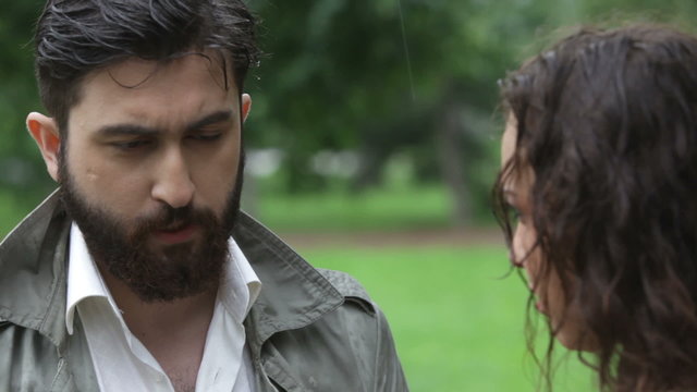 Close-up of bearded man proposing breakup under rain, disappointed woman walking away. Suitable for romance storytelling, cinematic scenes, relationship visuals and emotional content