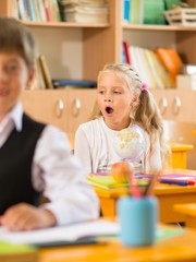 Bored little schoolgirl during lesson in school