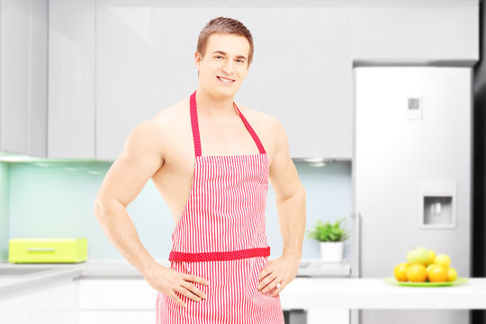Shirtless male cooker with apron posing in a kitchen