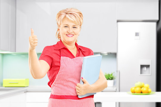 Female cooker in kitchen giving thumb up