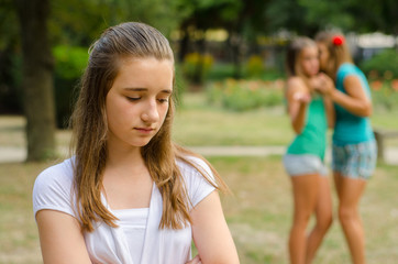 Two teenage girls making fun of the third