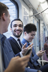 Three businessmen sitting in a row and talking on the subway