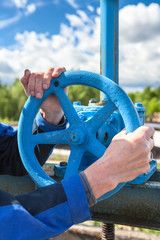 Hands close-up of mature manual worker turning stop-gate valve
